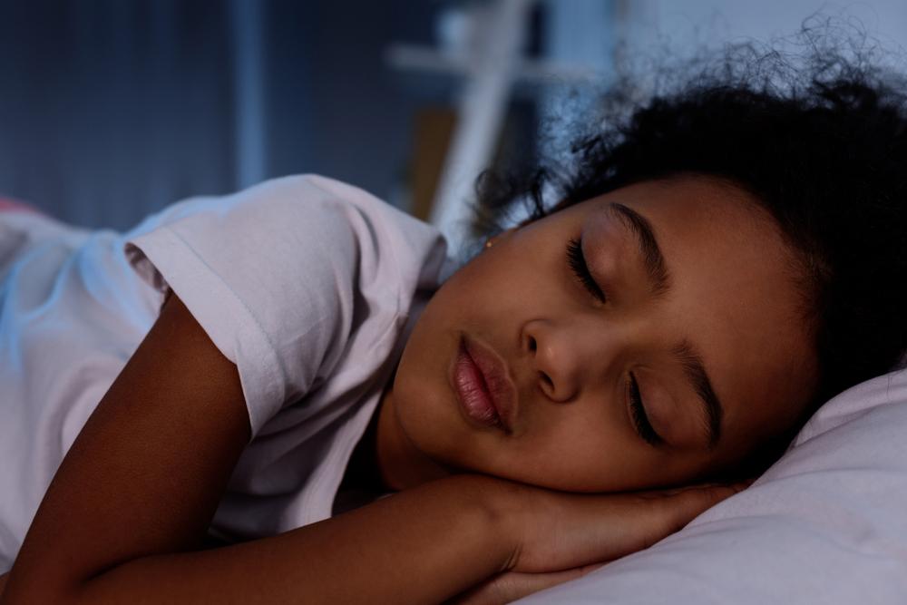 Young black girl asleep in bed.