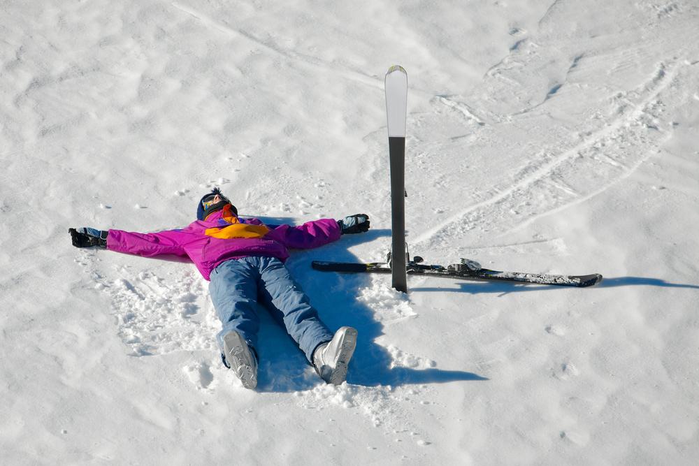 Young skiier laying in the snow.