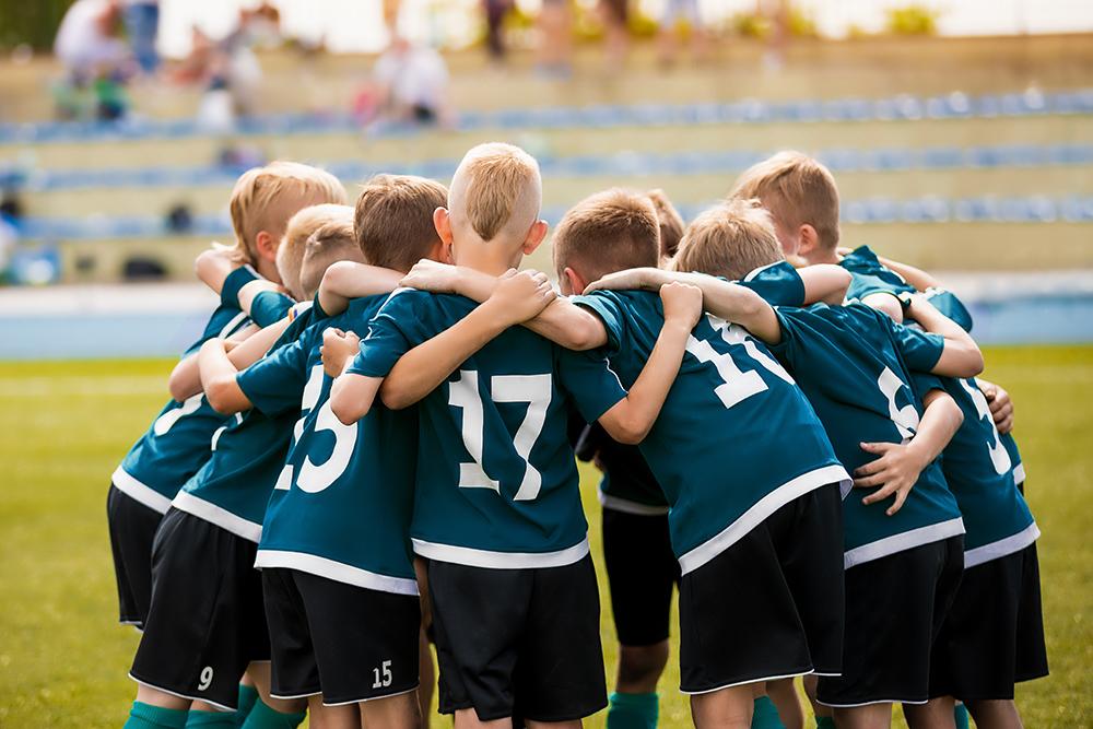 Young male kids in a huddle before a sports game.