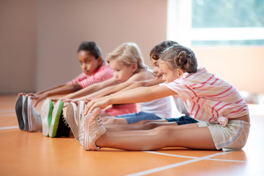 Group of diverse kids touching their toes.