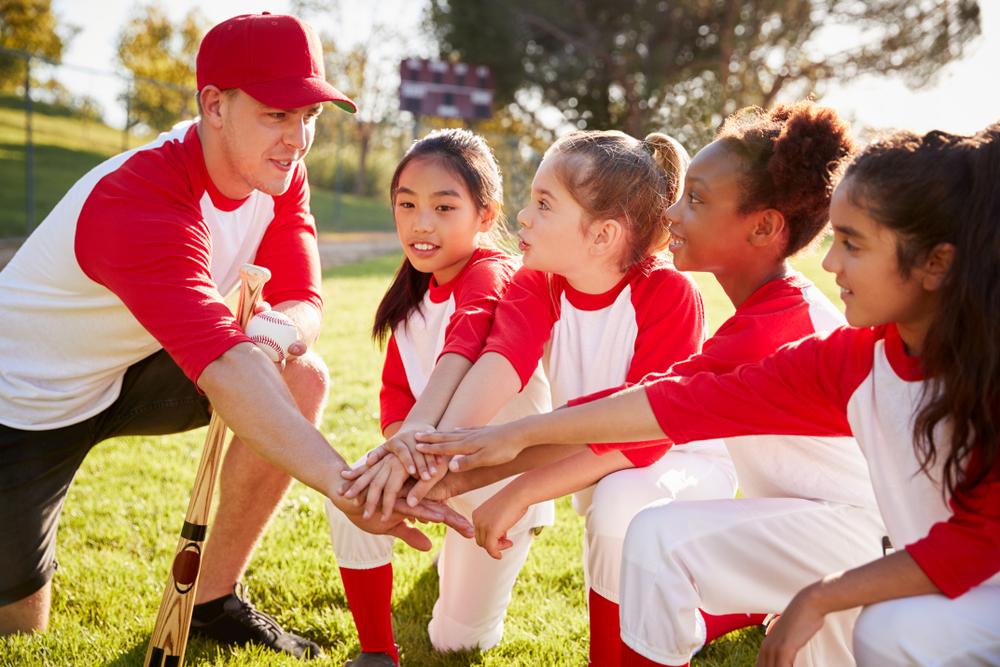 Girls softball team in a huddle with coach.