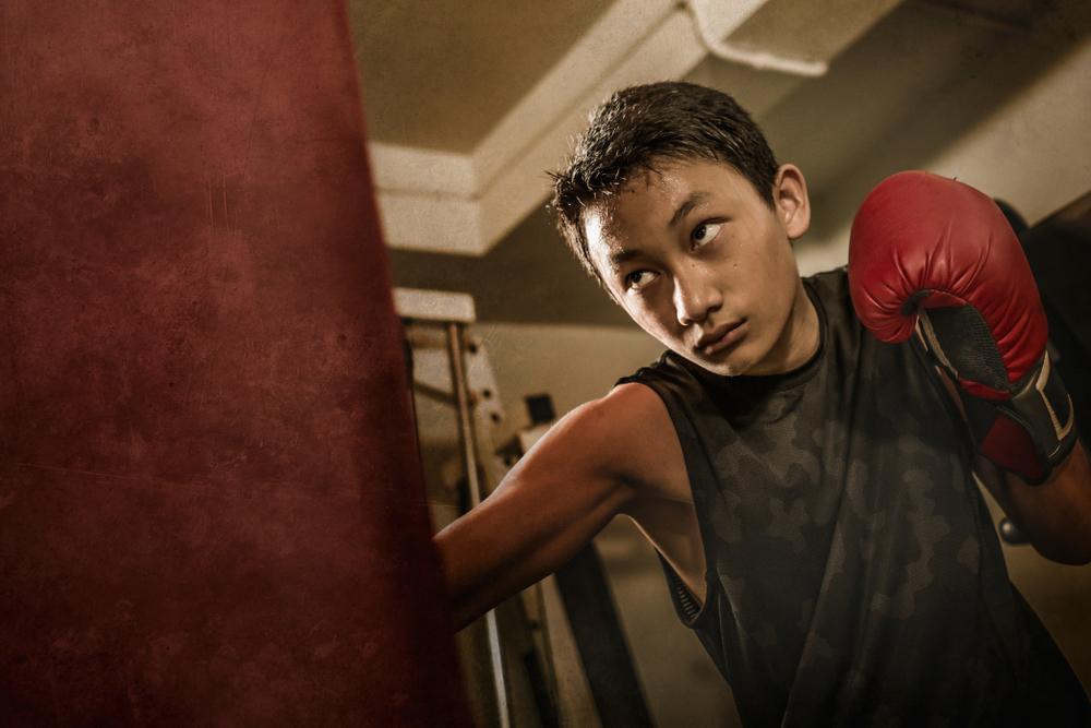 Young boy boxing and sweating.