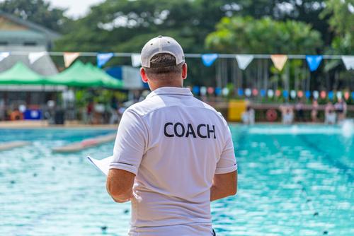 Male swim coach next to pool.