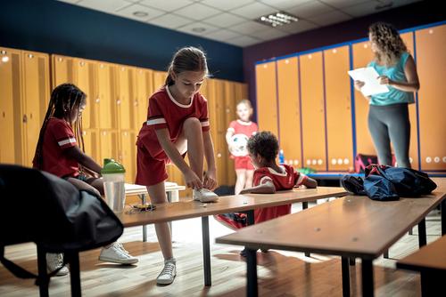 Young soccer team in locker room with coach.