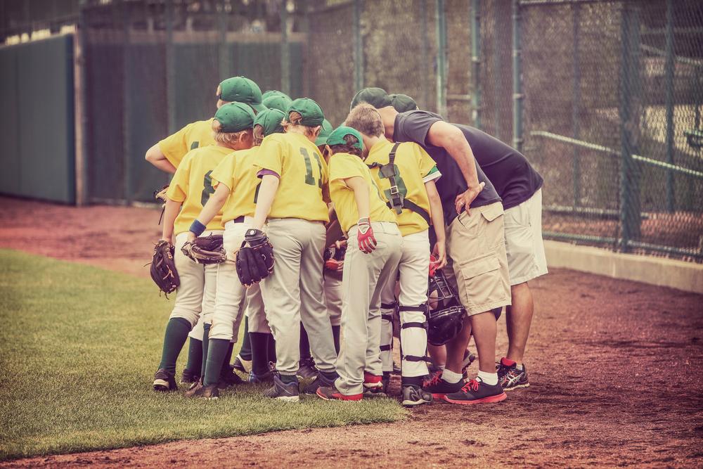 Young baseball team with coach in a huddle.