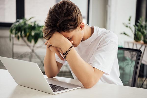 Young boy on laptop looking frustrated.