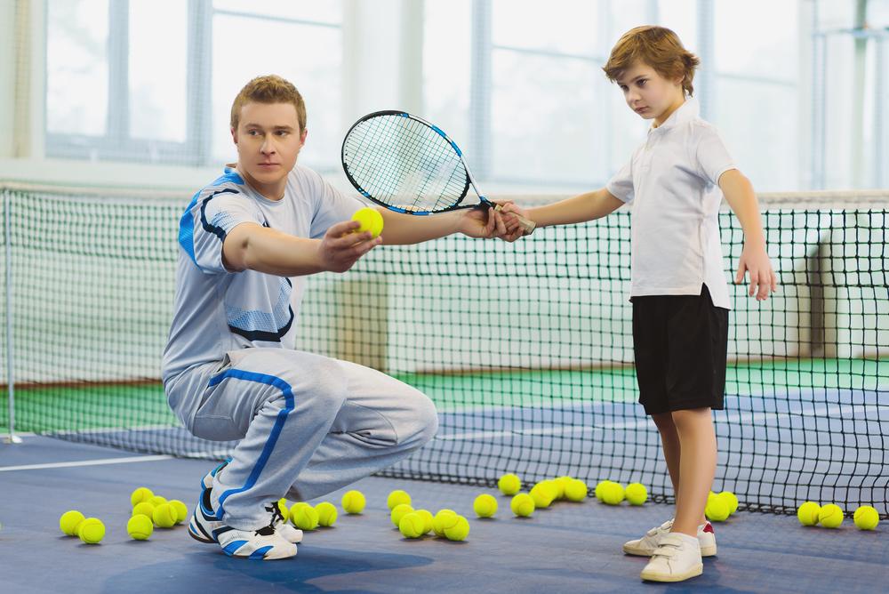 Tennis coach training with young male athlete.