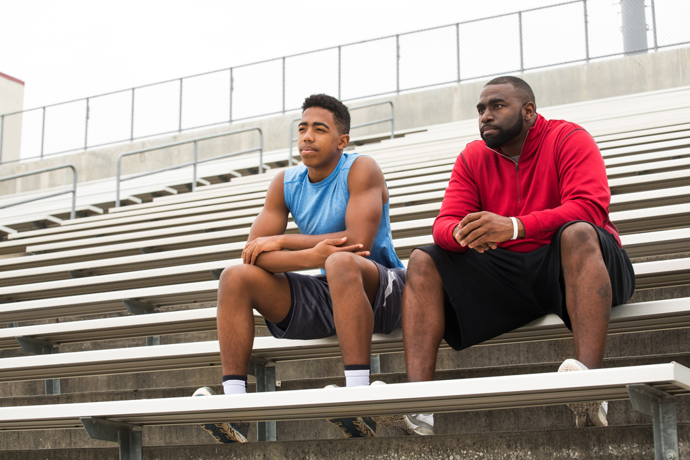 Teen boy and coach on bleachers.