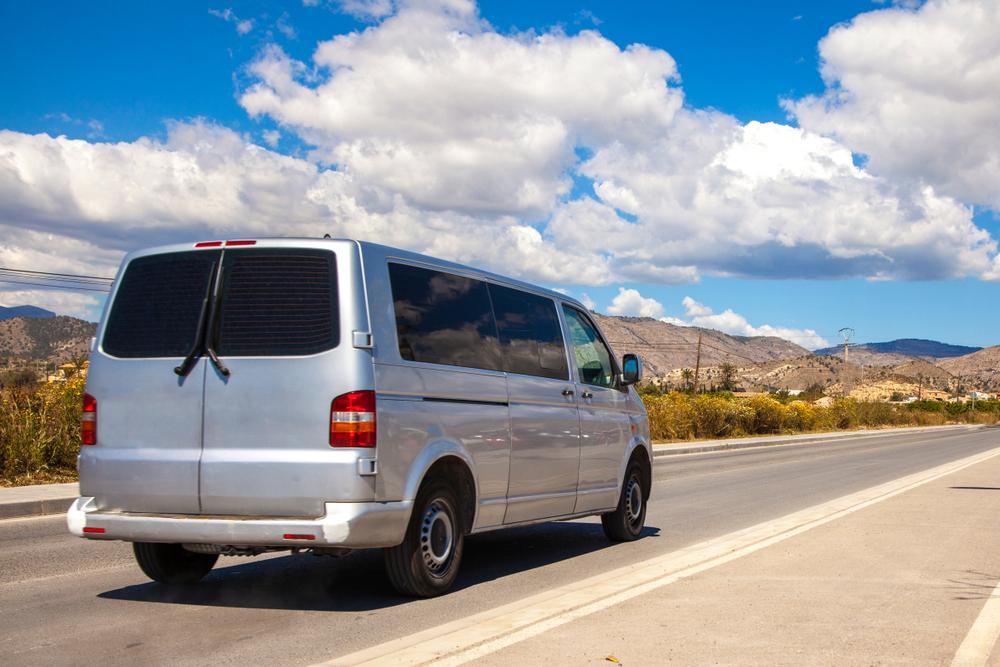 Minivan driving down a road.