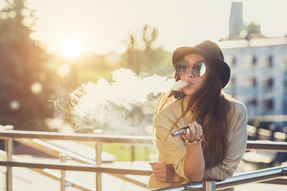 Young asian teen girl vaping.