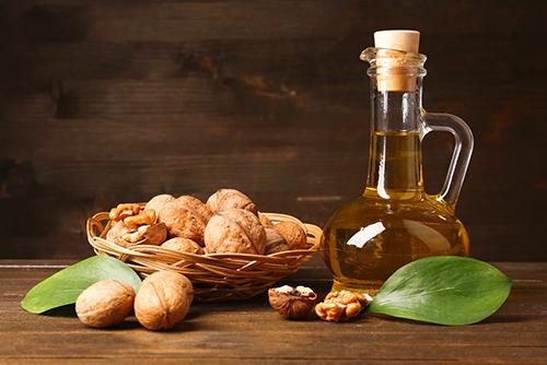 Walnuts next to walnut oil in glass.