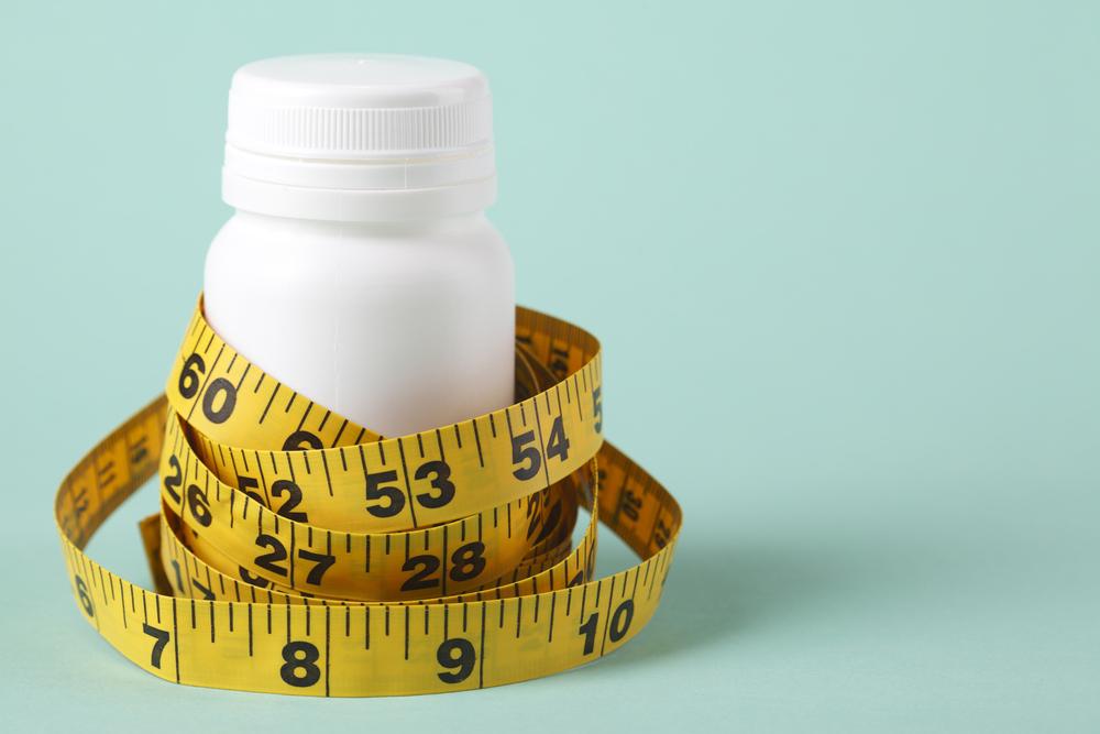 Tape measure around a white pill bottle.