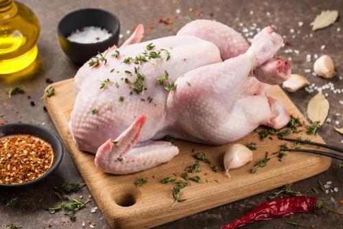 Raw whole chicken on cutting board.