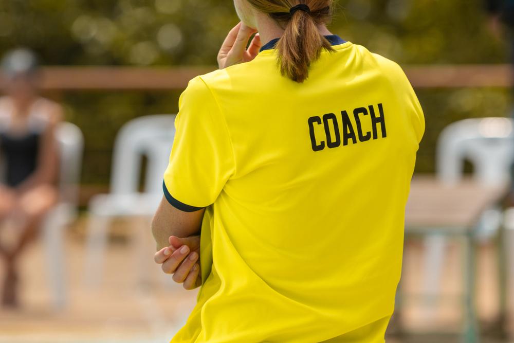 Close up rear view of female coach watching swim meet.