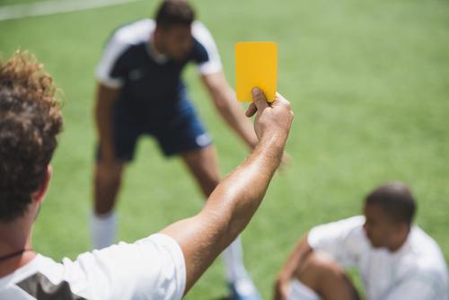 Soccer referee holding up a yellow card.