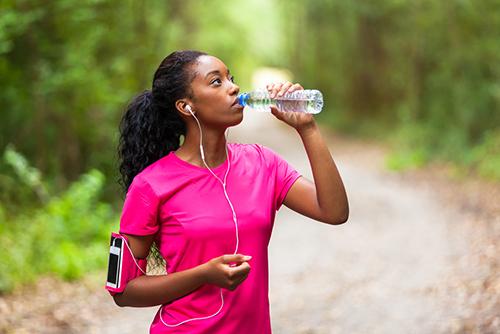 Young woman drinking water on a run.