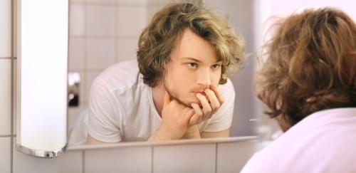 Young man looking in mirror.